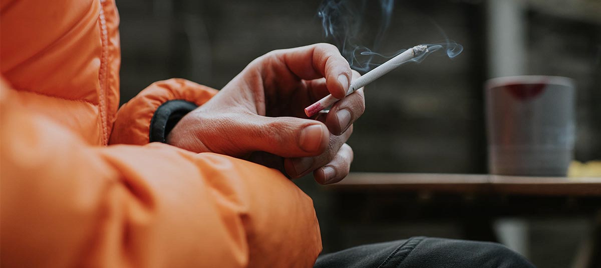 Smoking outside in orange jacket