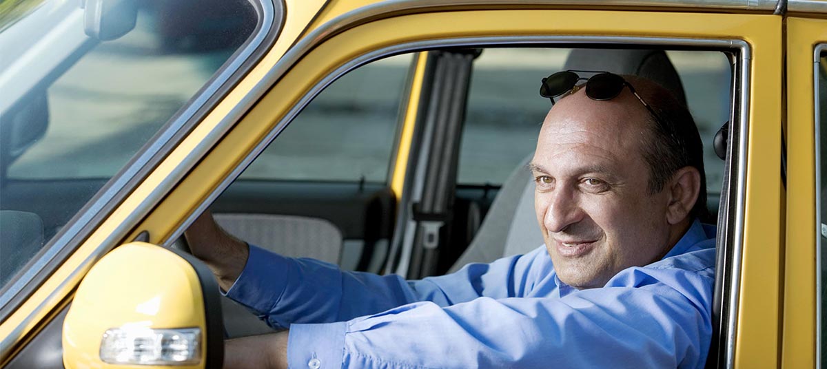 Man driving yellow car, smiling