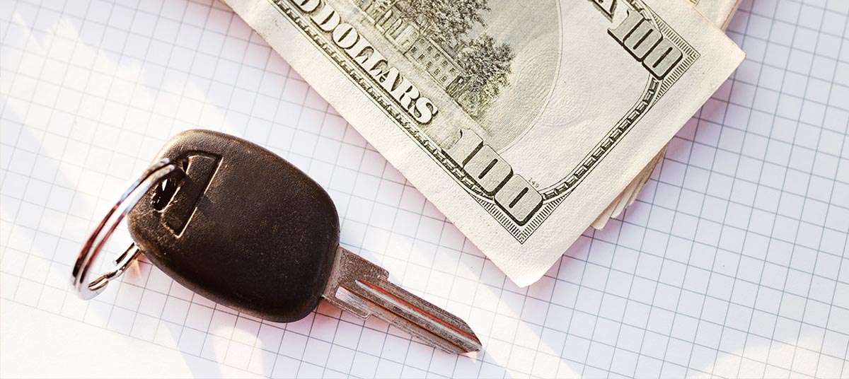 Vehicle key next to cash on grid paper
