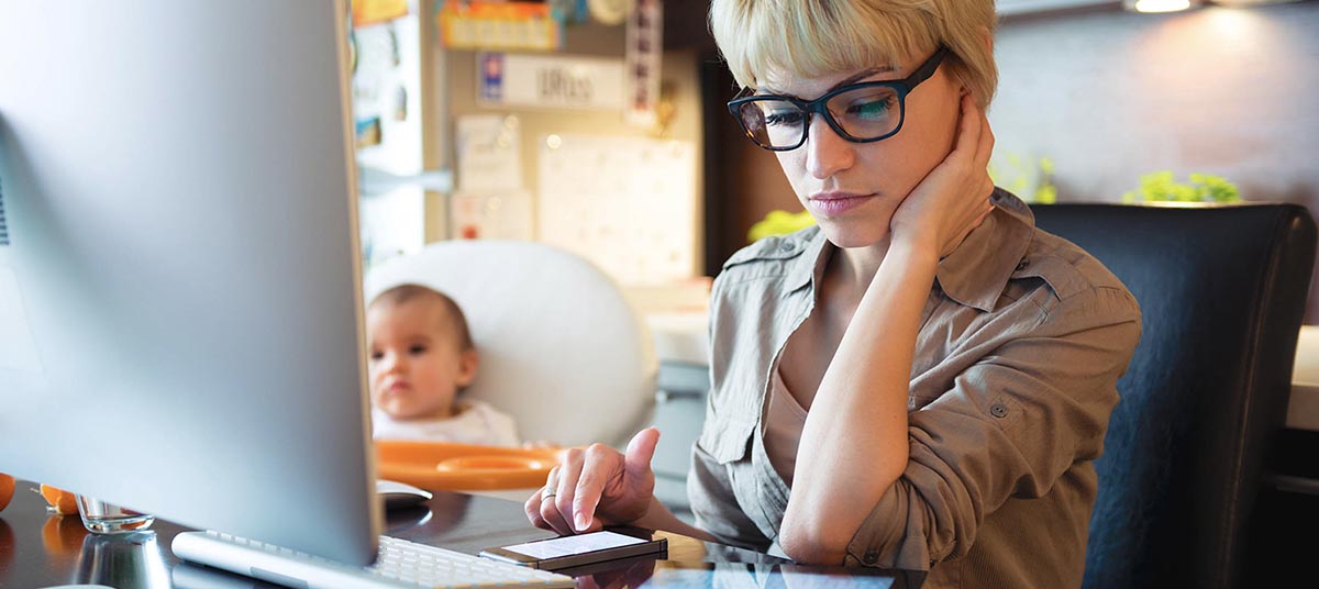 Woman working at computer with baby nearby