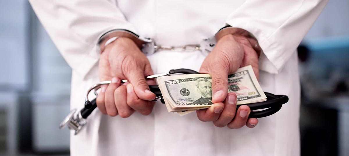 Handcuffed doctor with cash and stethoscope