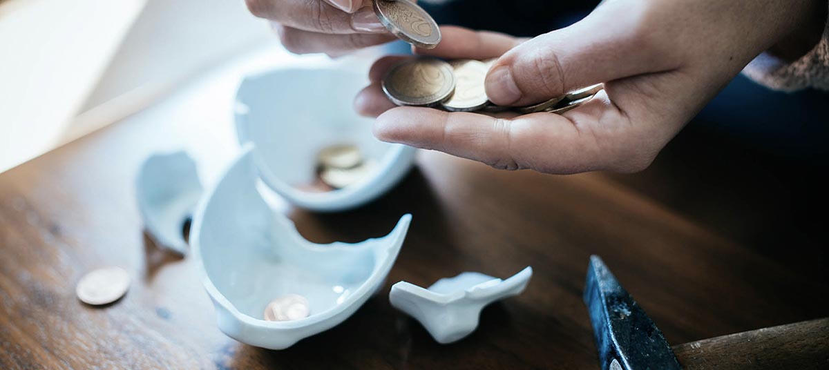 Person collecting coins from broken ceramic.