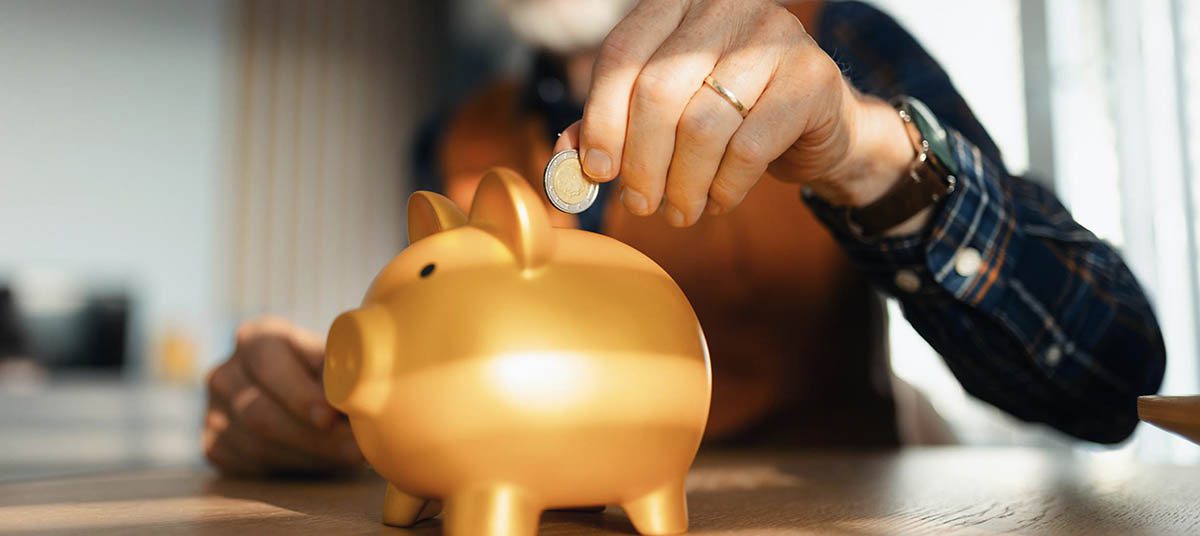 Hand placing coin in savings bank
