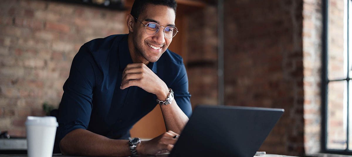 Man smiling while using a laptop