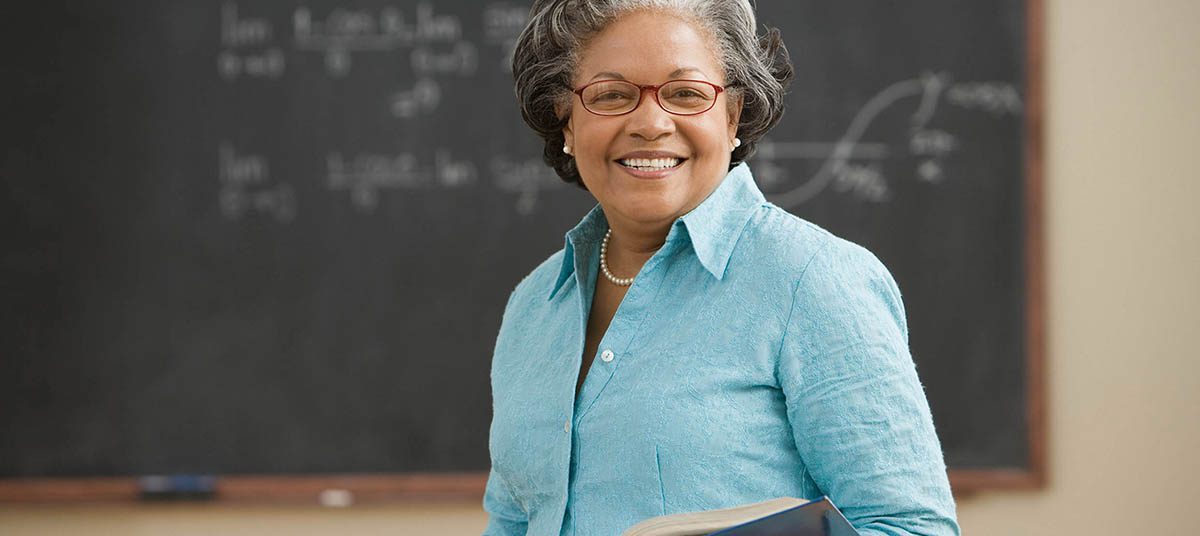 Smiling teacher in front of chalkboard