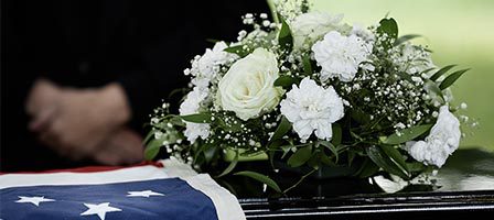 Funeral flowers on casket with flag