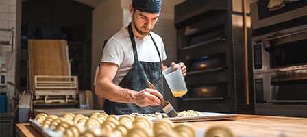Man glazing pastries in bakery