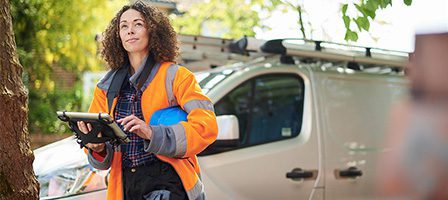 Utility worker holding tablet by work van
