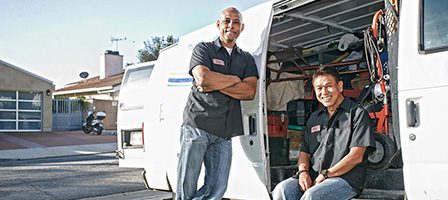 Smiling technicians near service van