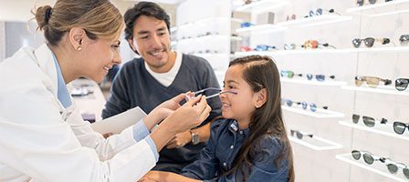 Optician fitting glasses on young girl
