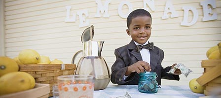 Child at lemonade stand with lemons
