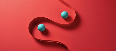 Two blue balls with red ribbon curve.