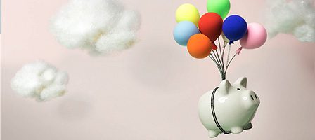 Piggy bank floating with colorful balloons