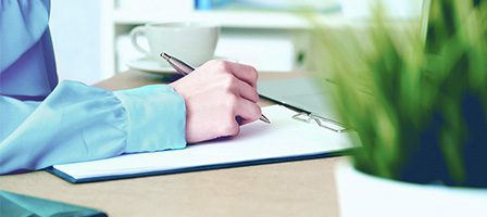 Hand holding pen over paper