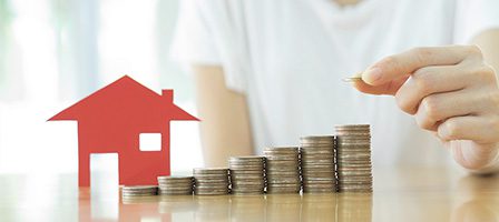 Red house and stacked coins on table