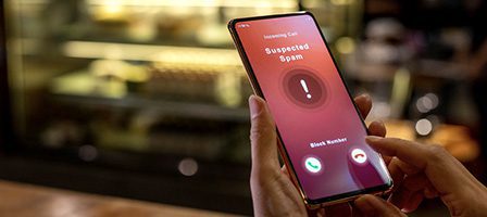 Person holding phone with spam call notification