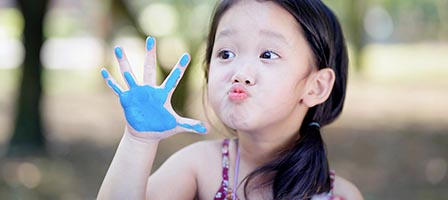Child with blue paint on hand