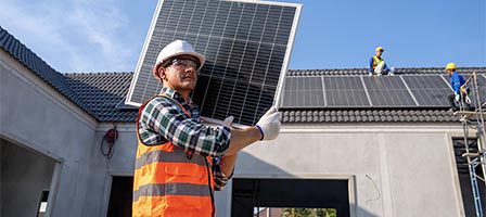 Worker holding solar panel on roof