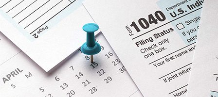 Blue pushpin on tax paperwork