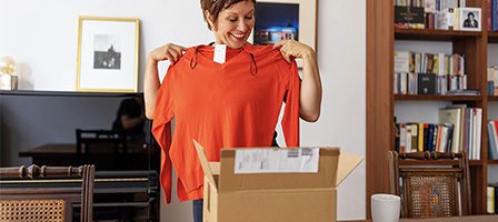 Smiling woman unpacking clothing delivery