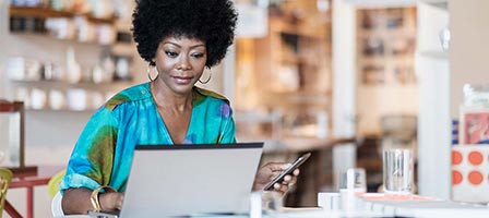 Woman working on laptop and phone
