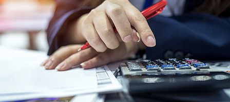Hand using calculator on documents