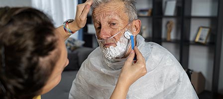 Caregiver assisting with elderly man's shave.