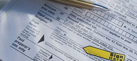 Tax paperwork with signature indicator and pen