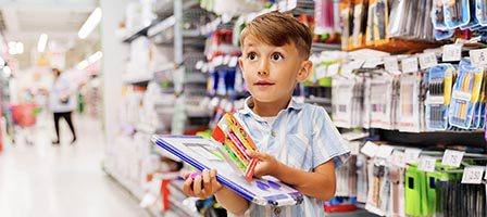 Young boy holding notebooks and pens