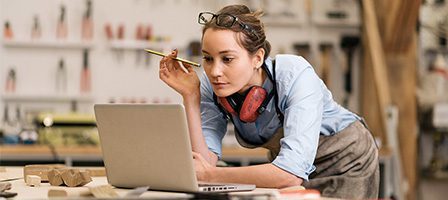 Focused crafter using laptop in studio